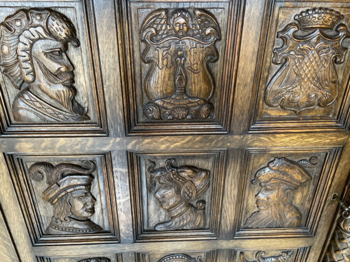 Antique Cabinet With Carved Coats Of Arms And Heads On The Front
